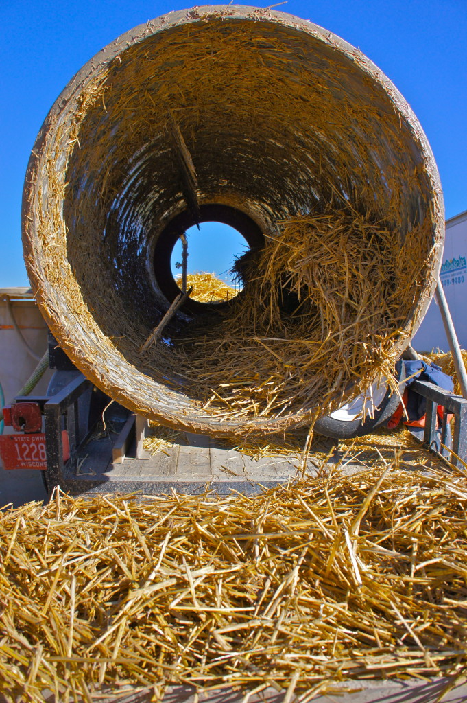 The mixer tumbling the straw to coat it lightly with clay.